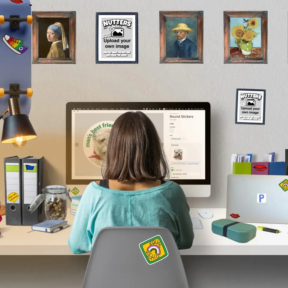 Person sitting at a desk designing personalised stickers online with personalised stickers and wall art stickers decorating home workspace